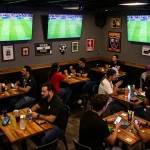 Socolive fans placing bets on mobile devices while enjoying live soccer games at a sports bar